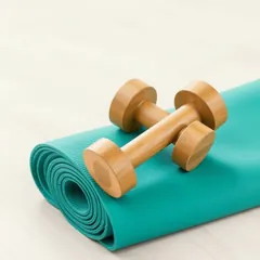A rolled teal yoga mat with a dumbbell