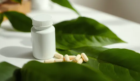 A white supplement bottle with capsules and leaves