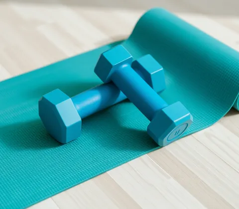 Blue dumbbells resting on a teal yoga mat