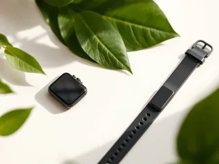 A square smartwatch next to a slim fitness band