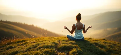 A woman meditating on a hilltop at sunrise
